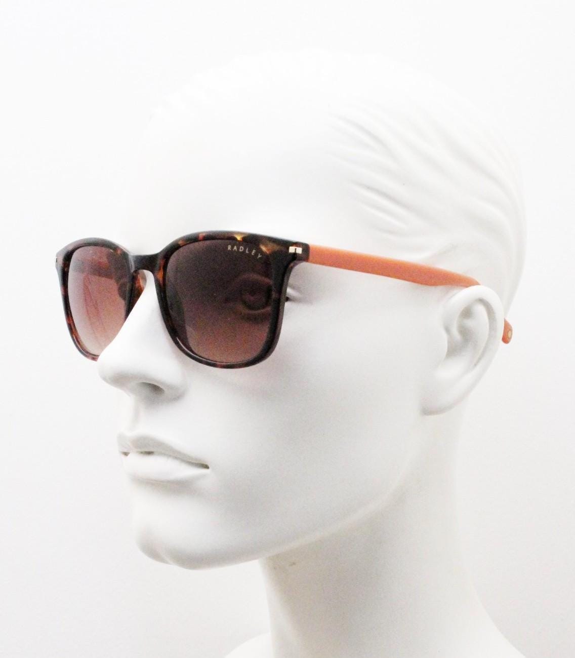 Modified wayfarer design sunglasses by Radley. Tortoise front with bright orange arms and Havana brown lenses. Vintage. Unused NOS