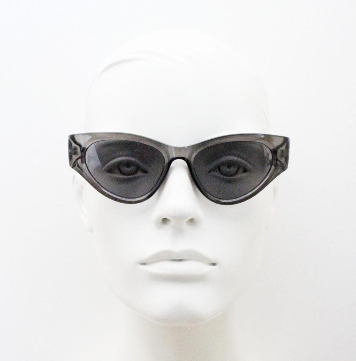 Thick cateye sunglasses with cropped sides and sharp outline. Womens 60s design chunky transparent grey frame and lenses. Y2k vintage
