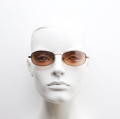May include: A white mannequin wearing brown rectangular sunglasses with a thin metal frame.