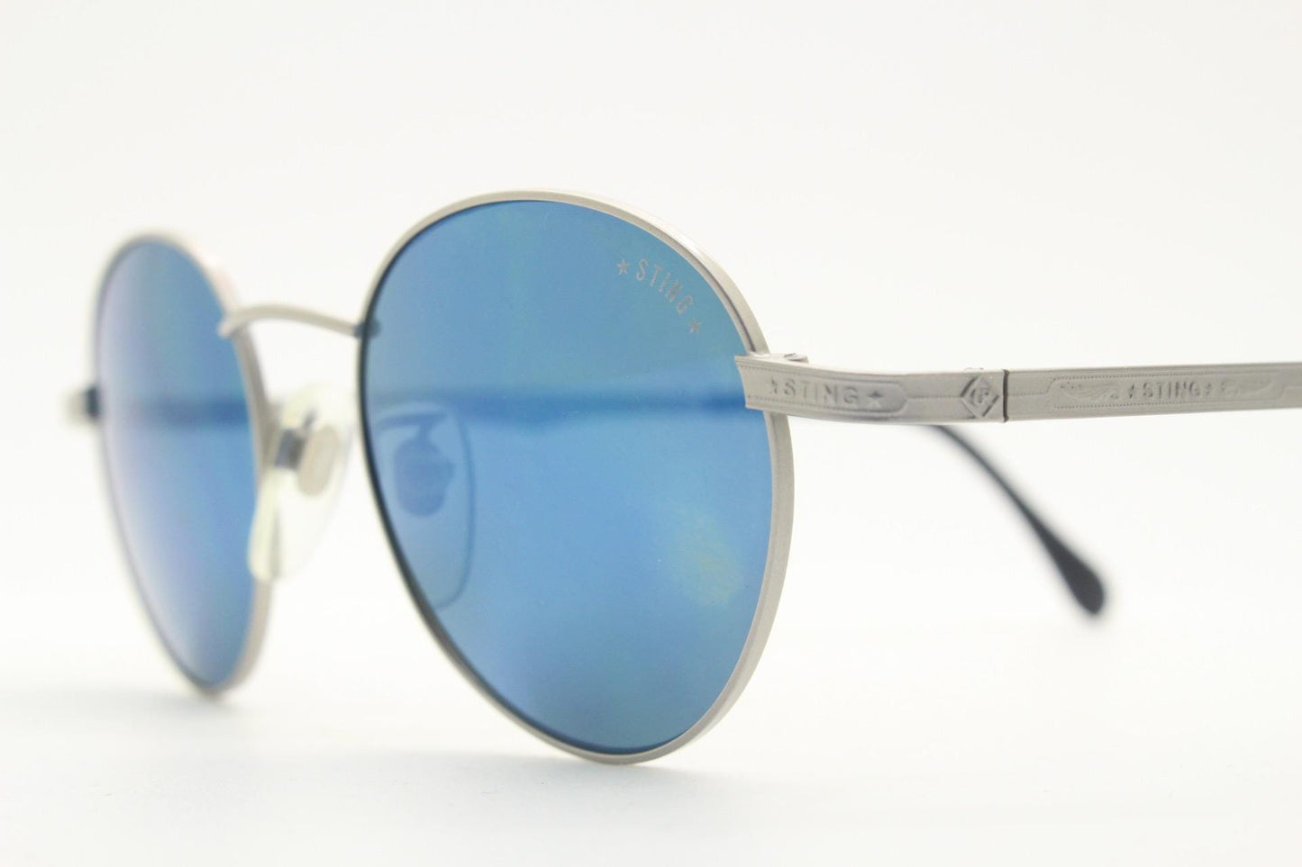 Sting 90s vintage oval sunglasses made in Italy. Minimal grey aluminium look in slightly small proportions with blue mirror lenses