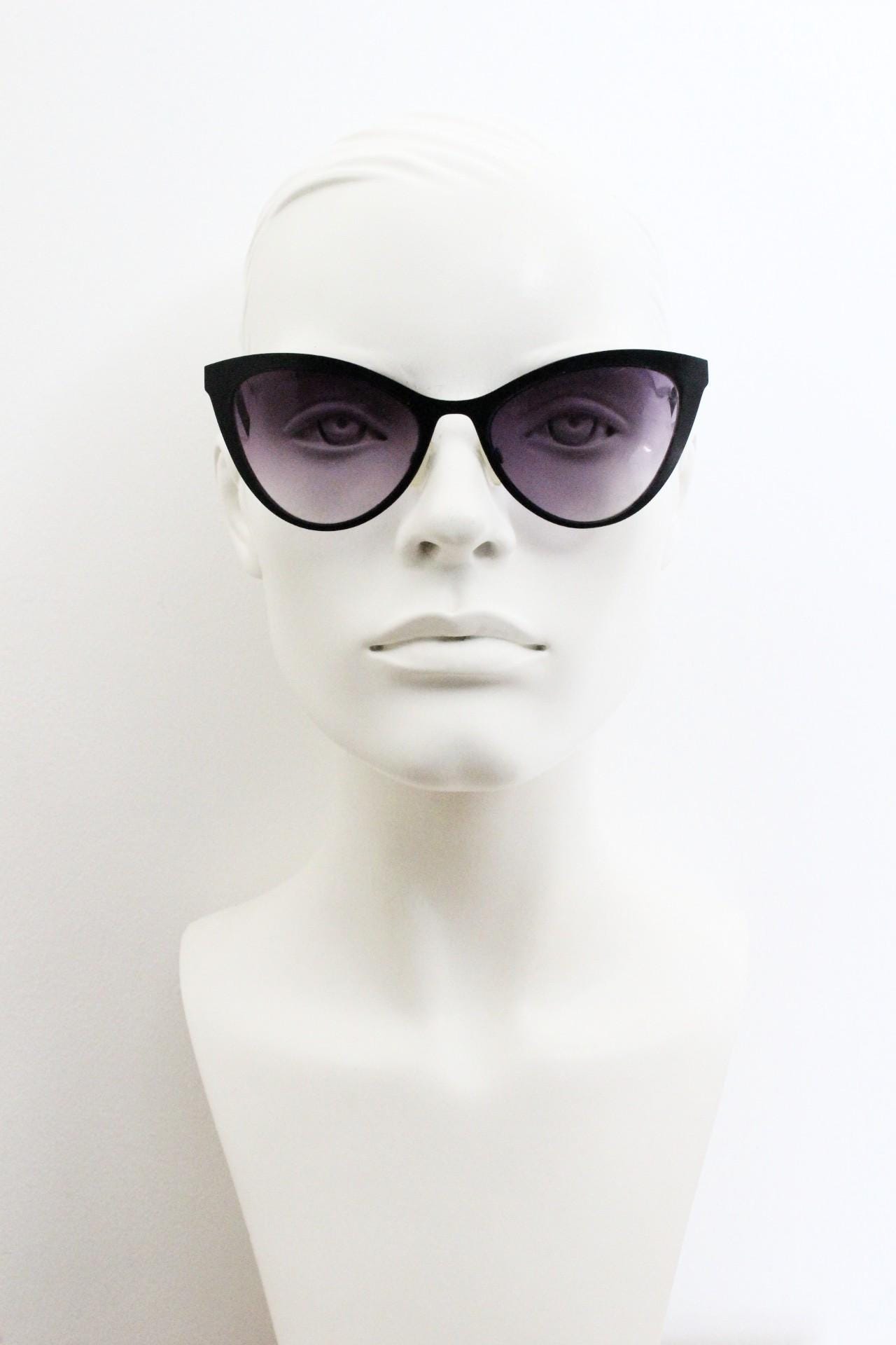 Vintage pointed cat eye sunglasses. Flat metal frame in a satin finish encasing smoky grey graduating lenses. Womens cateye