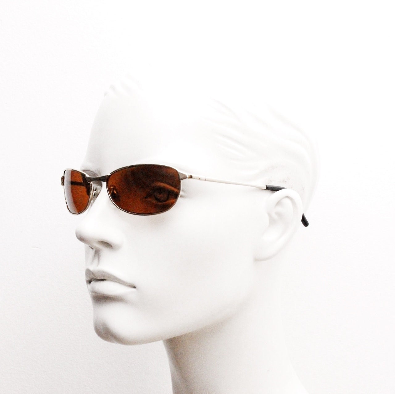 90s vintage curved angular oval sunglasses. Solid metal small bug eye frame in gold chrome with mid tone brown lenses. 2000's. Y2K NOS