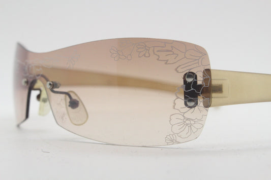 Y2K vintage visor sunglasses. Frameless 2000's wraparound mini mask shield design with light tone mono lens and flower print. 00s NOS