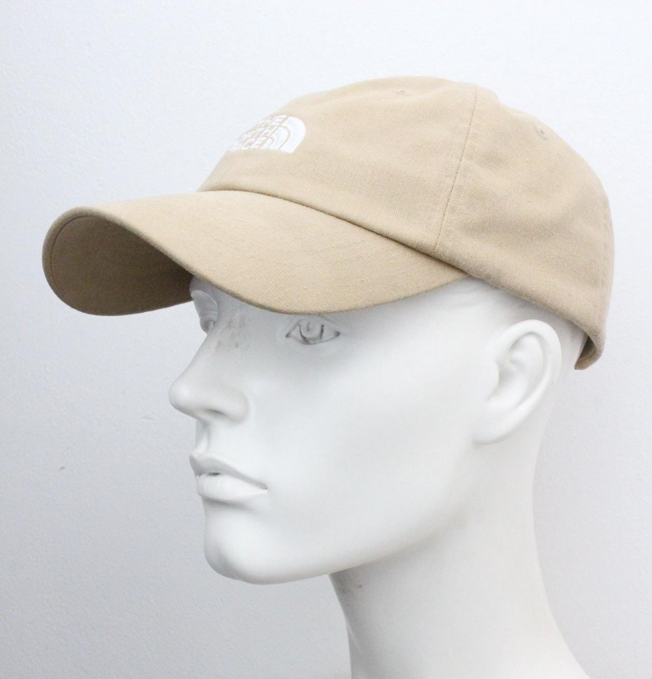 The North Face beige / sand colour baseball cap with white spell out logo. Classic trucker style hat with fully adjustable back. One size