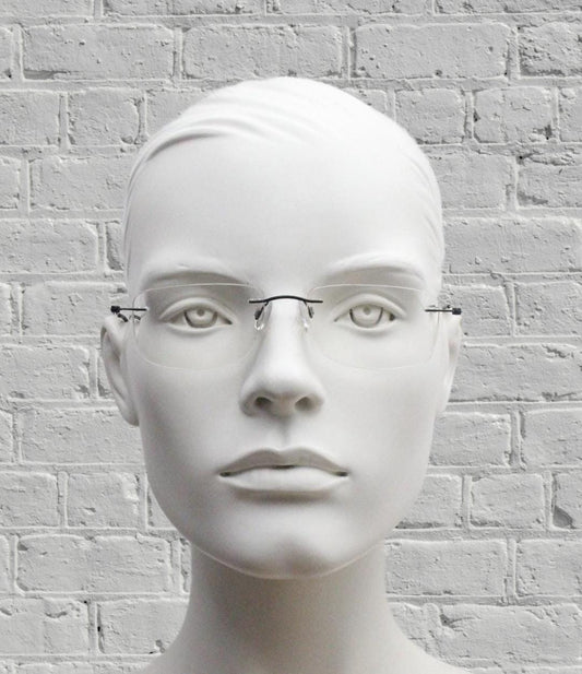A white mannequin head wearing glasses against a white brick wall background.