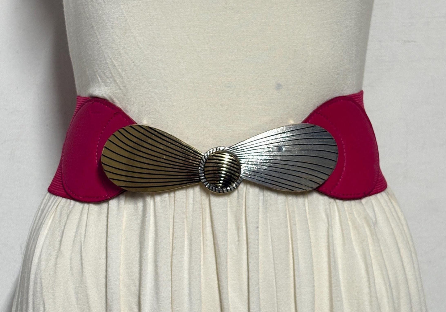 80s vintage womens tall pink elastic belt. Large winged silver and gold buckle. Flattering cinch effect. Adjustable stretchy size range