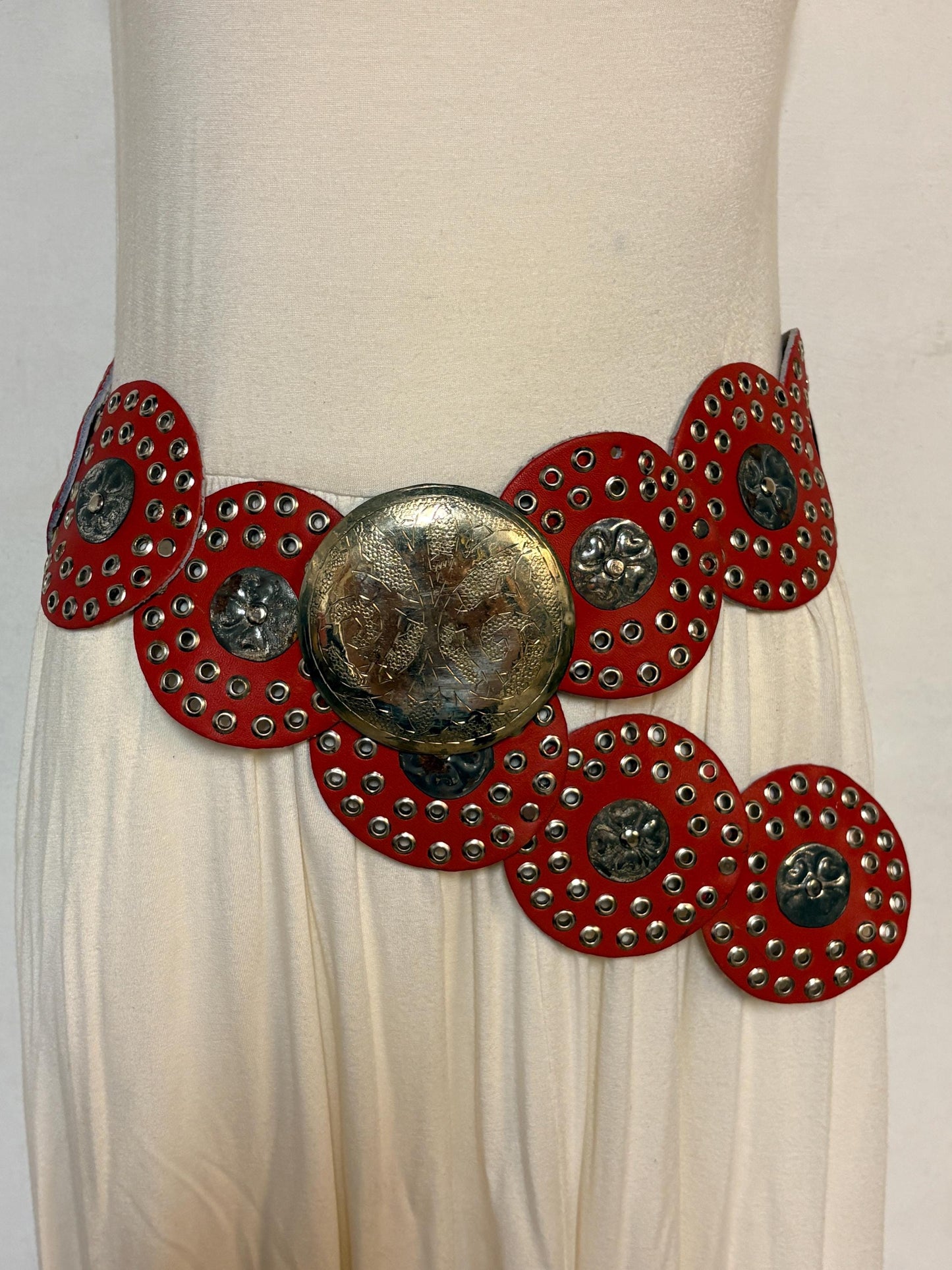 80s vintage womens huge red leather circles belt. Versatile statement piece with holed studs, metal discs and big 'shield' buckle. NOS