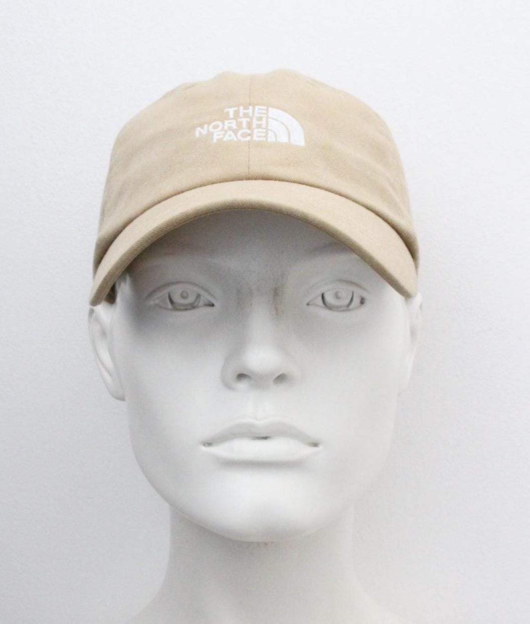 The North Face beige / sand colour baseball cap with white spell out logo. Classic trucker style hat with fully adjustable back. One size