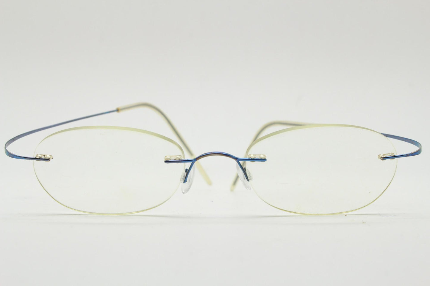 Frameless vintage oval eye glasses. Extremely minimal lightweight blue titanium optical frame with springy hingeless arms. 2000s