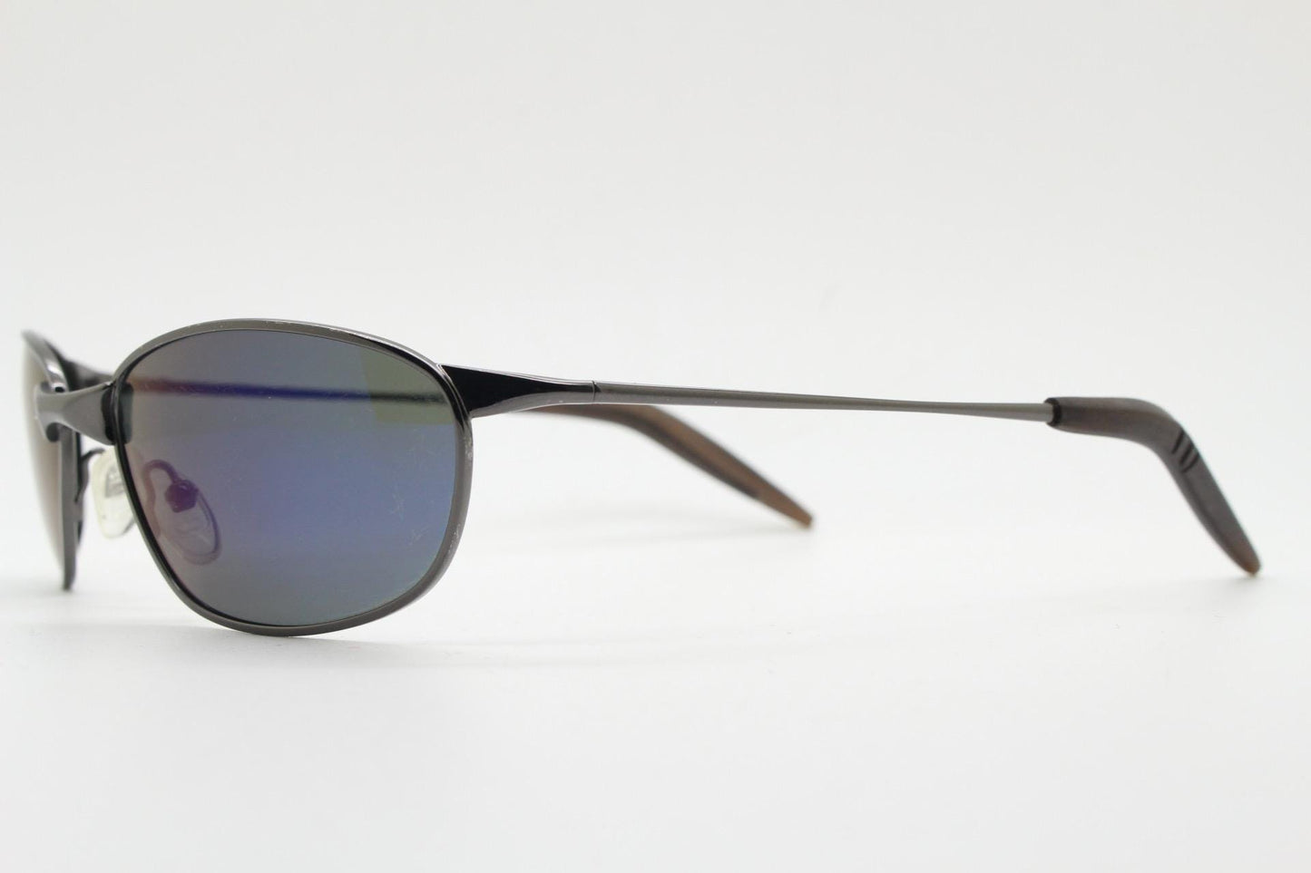 90s vintage curved oval sunglasses. Solid metal low profile frame in grey chrome with slightly mirrored dark lenses. 2000's. Y2K NOS