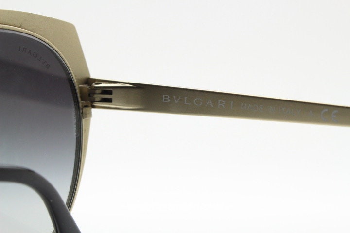 Bulgari round cropped cat eye sunglasses made in Italy. Womens black and gold frame with honeycomb patterns and smoky graduating lenses