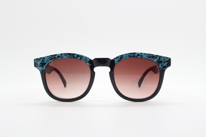 80s vintage rounded wayfarer design sunglasses. Abstract patterned blue brow and arms on a black frame with graduating  lenses. Unused NOS